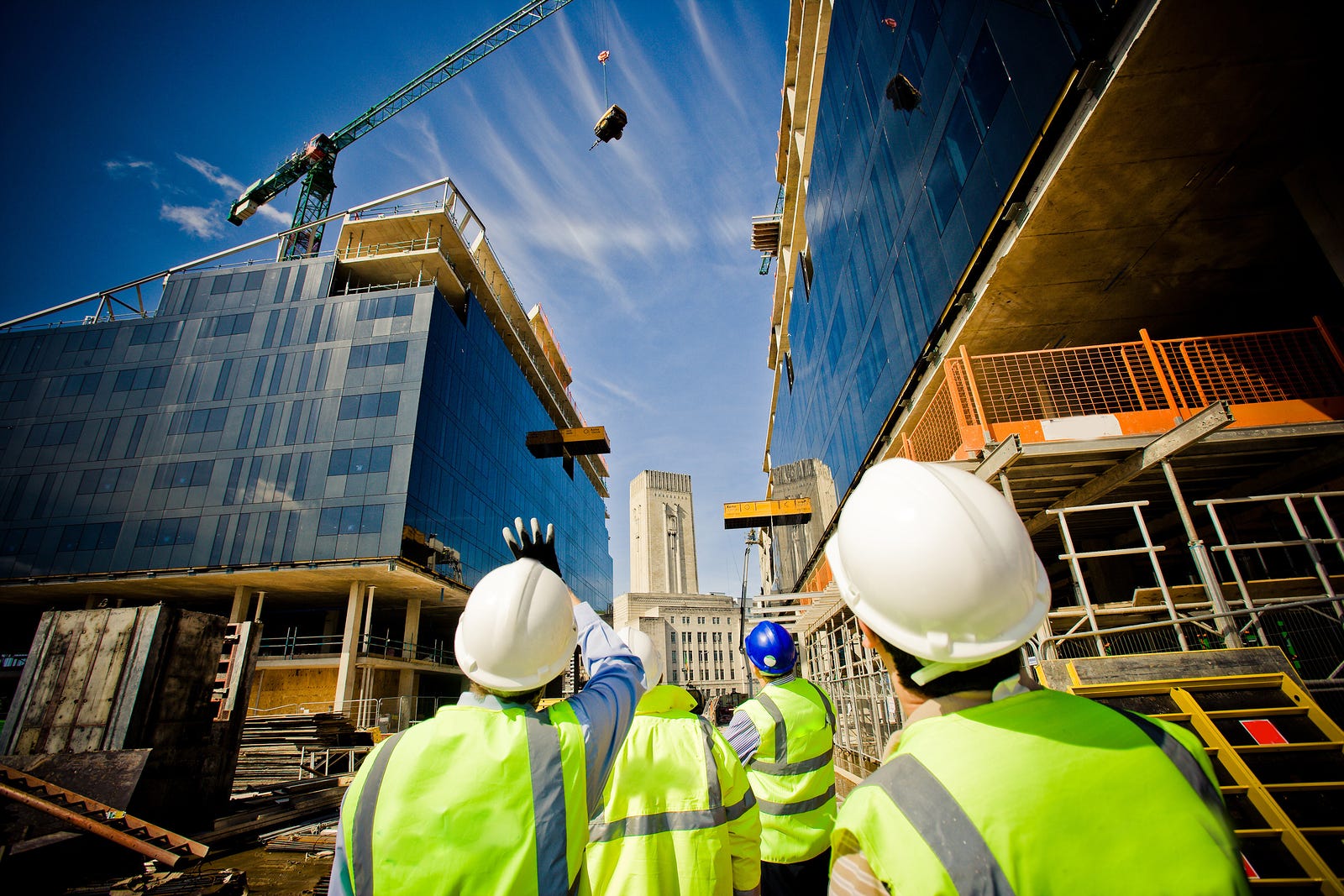 Construction workers looking up at a modern building under construction with a crane.